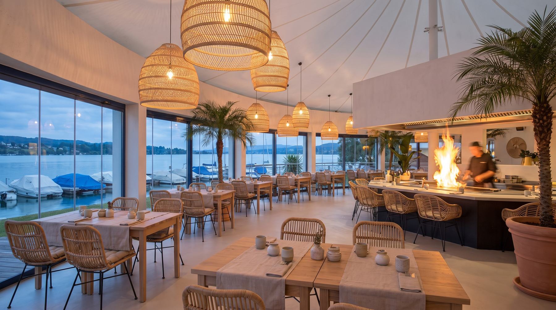 Sala interna della Vela Bianca con lampade in rattan e vista sul porto